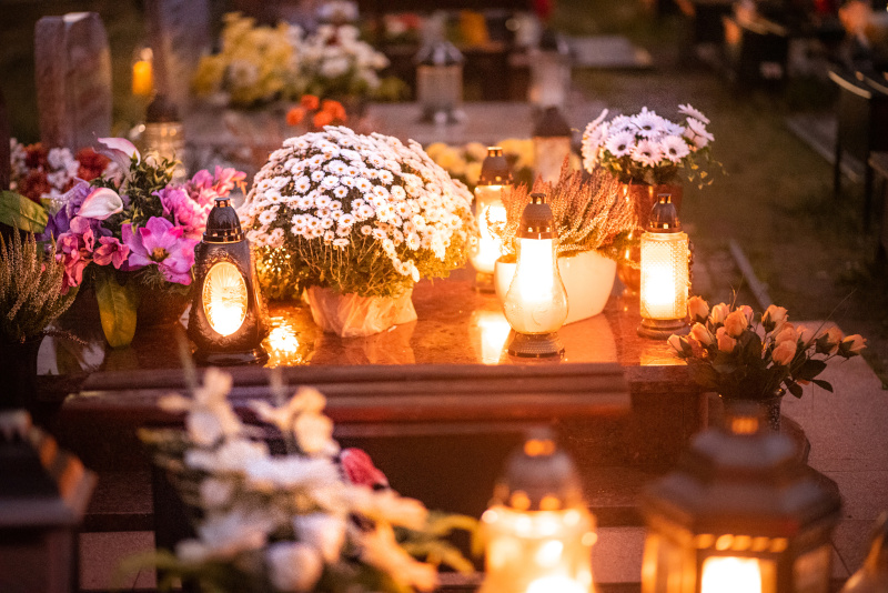Blumen und Kerzen auf einem Grab an Allerheiligen.